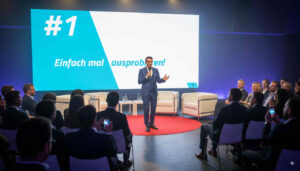 KI-Speaker und Business-Moderator Ferry van Saalbach steht vor einem Publikum und hält eine Präsentation.